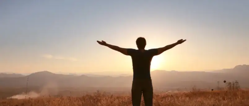 A man raised his arms in front of sun